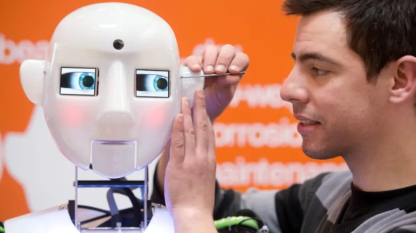 epa03652578 An employee adjusts a humanoid robot at the Hanover Fair in Hanover, Germany, 07 April 2013. About 6,500 companies take part in the world's biggest industrial technology exhibition Hanover Fair (Hannover Messe) from 08 to 12 April 2013. EPA/JOCHEN LUEBKE