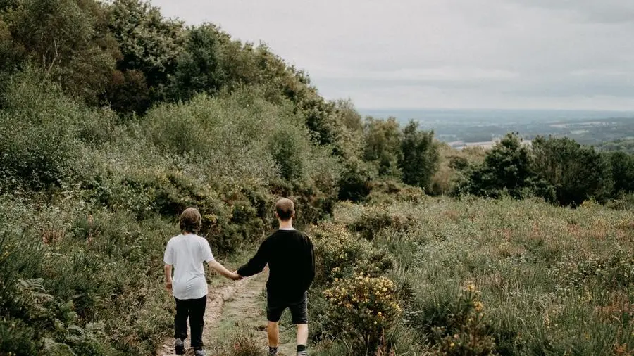 Due persone si tengono per mano in campagna - Foto Unsplash