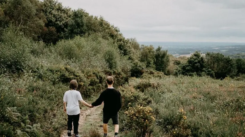 Due persone si tengono per mano in campagna - Foto Unsplash