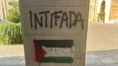 La scritta Intifada con la bandiera palestinese e la A anarchica fuori dalla sede di Azione a Brescia