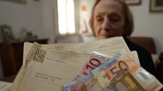 Un'anziana alle prese con soldi e documenti - © www.giornaledibrescia.it