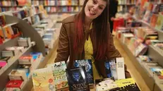 Sara Cremini in una libreria insieme ai suoi romanzi - © www.giornaledibrescia.it