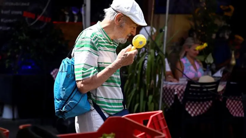 Un uomo cerca sollievo con un ventilatore portatile - Foto Ansa/Epa/Riccardo Antimiani © www.giornaledibrescia.it