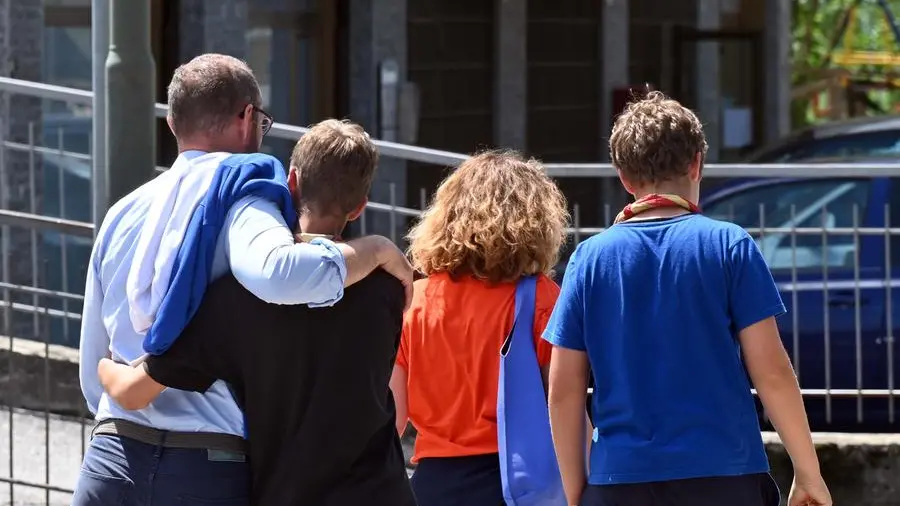 Due ragazzi si aggrappano ai genitori, venuti a prenderli per riportarli a casa - Foto Gabriele Strada/Neg © www.giornaledibrescia.it