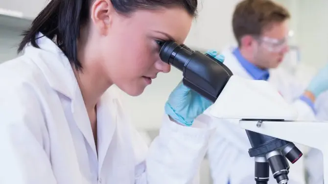 Una giovane ricercatrice al microscopio: crescono le eccellenze femminili in campo scientifico