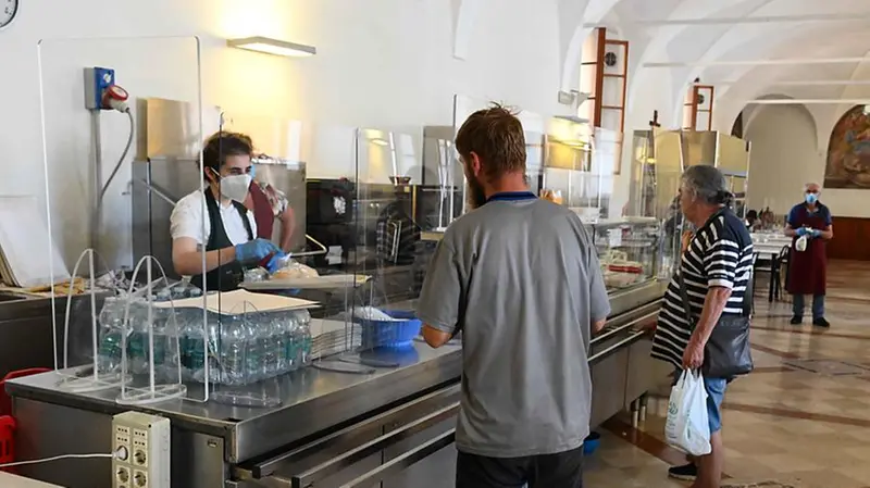 Una volontaria serve il pranzo a due avventori - Foto Marco Ortogni/Neg © www.giornaledibrescia.it