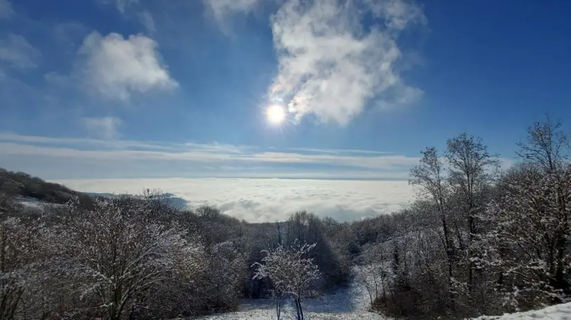 La città coperta dalle nubi, osservata da un monte Maddalena innevato
