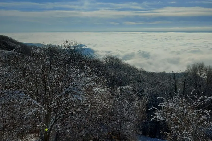 La città coperta dalle nubi, osservata da un monte Maddalena innevato