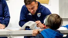 Davide Adorni firma un cappellino per un bambino al Brescia Store - Crediti Brescia Calcio
