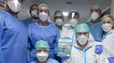 Un gruppo di operatori sanitari con il libro di AiutiAMObrescia - © www.giornaledibrescia.it