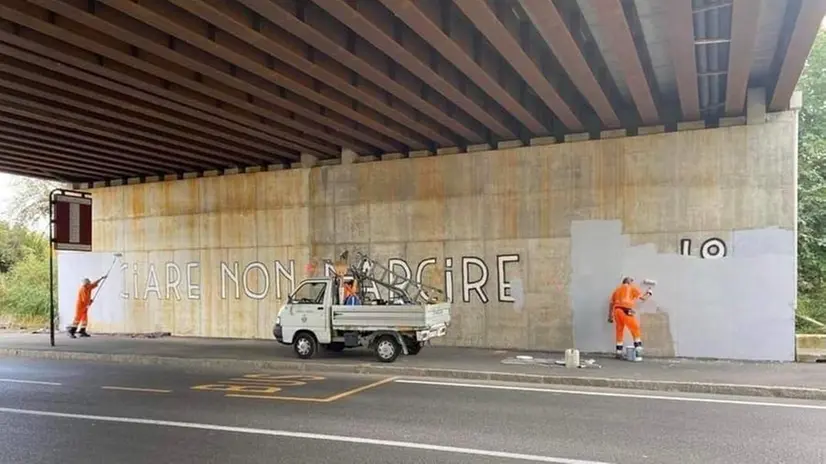 Gli operai comunali mentre cancellano la scritta