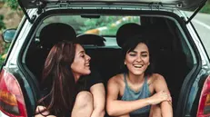 Due ragazze sedute nel bagagliaio di un'auto