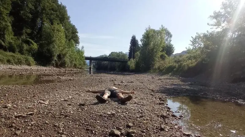 Un uomo sdraiato sul letto del fiume Chiese, in secca - © www.giornaledibrescia.it