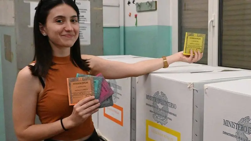 Una ragazza inserisce le schede del referendum sulla giustizia nei box