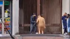 Via Milano, l'uomo nudo in strada riceve da un passante un paio di pantaloncini con cui coprirsi (immagine tratta dal frame di un video inviato da un lettore)
