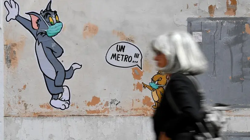 Una passante davanti ad un murales con Tom & Jerry in versione pandemica - © www.giornaledibrescia.it