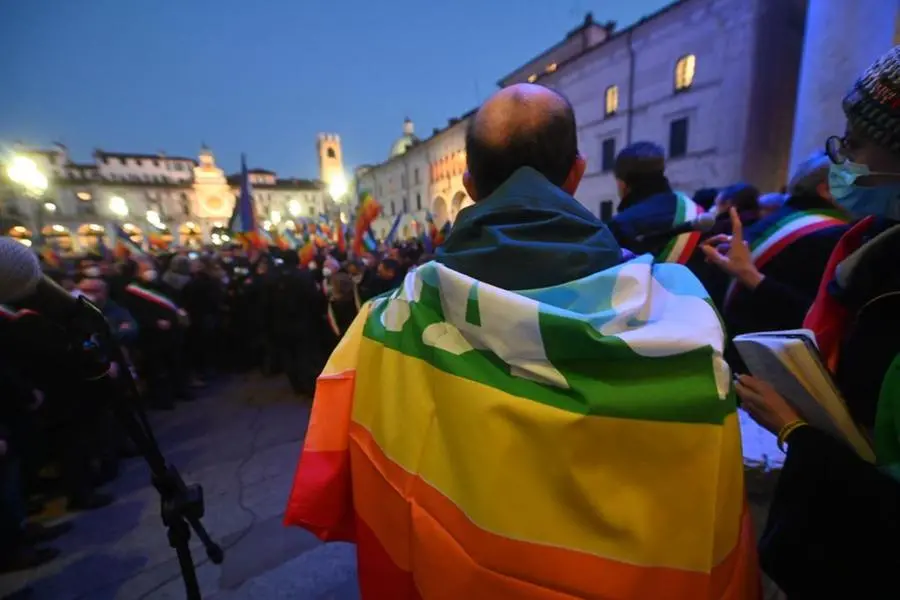 Un uomo indossa una bandiera della pace in piazza Loggia al presidio contro la guerra in Ucraina - Foto Marco Ortogni/Neg © www.giornaledibrescia.it