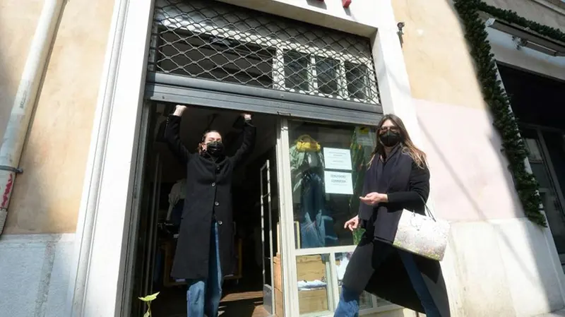 Due ragazze alzano la saracinesca del loro negozio alla fine del lockdown - Foto Marco Ortogni/Neg © www.giornaledibrescia.it