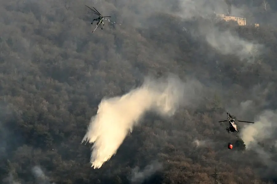 Un elicottero sorvola il fianco della Maddalena gettando acqua sull'incendio