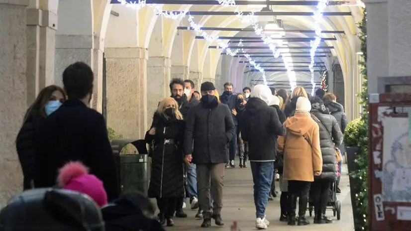 Persone a passeggio sotto i portici di via X Giornate addobbati per Natale - Foto Marco Ortogni/Neg © www.giornaledibrescia.it