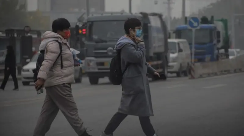 Due persone camminano per strada a Pechino indossando la mascherina. - © Foto Epa/ Wu Hong