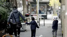 Un padre con i suoi figli passeggiano per strada - Foto Ansa  © www.giornaledibrescia.it