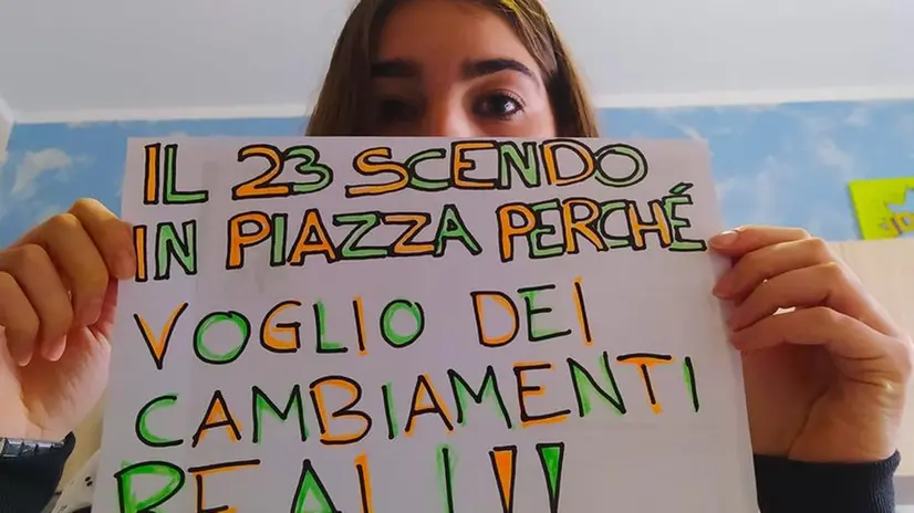 Una ragazza regge un cartello con cui aderisce all'iniziativa di protesta