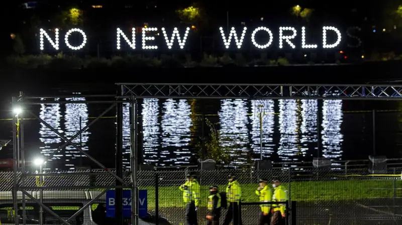 La polizia cammina davanti alla scritta No New World a Glasgow - Foto Epa © www.giornaledibrescia.it