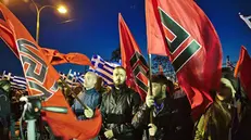 Militanti di Alba Dorata in Grecia sventolano le bandiere con il meandros