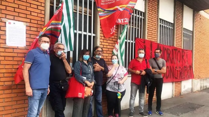 Sindacati e dipendenti accanto allo striscione che recita: «I lavoratori non sono rifiuti» - © www.giornaledibrescia.it