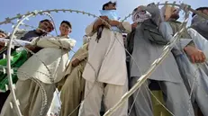 Persone ammassate dietro il filo spinato all'aeroporto di Kabul
