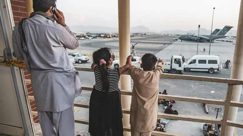 Un padre afghano all’aeroporto con i suoi due figli - Foto Ansa © www.giornaledibrescia.it