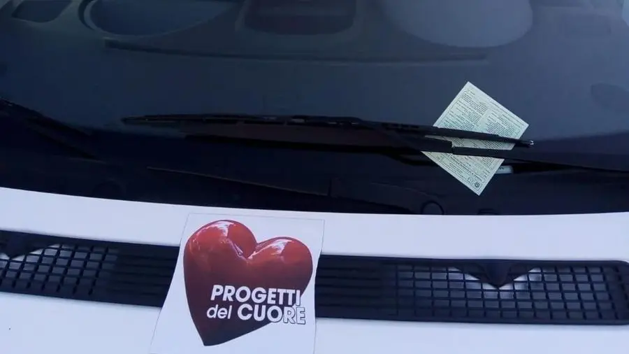 Il verbale della contravvenzione posto sotto il tergicristallo del pullmino usato per il trasporto disabili - © www.giornaledibrescia.it