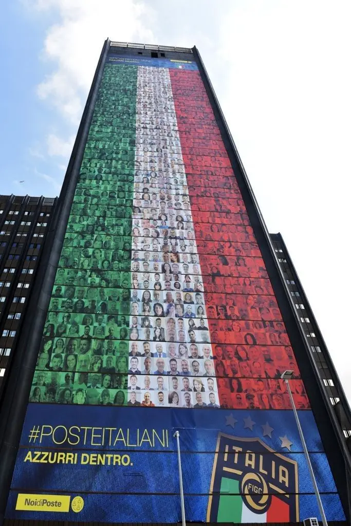 La maxi bandiera di Poste issata sulla sede centrale di Roma