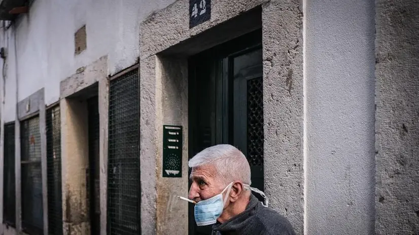 Un uomo fuma una sigaretta dopo aver abbassato la mascherina - Foto Epa/Mario Cruz