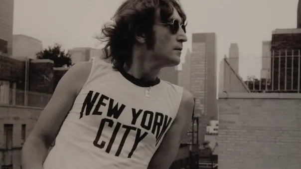John Lennon in uno scatto che lo ritrae a New York (con maglietta della città) © www.giornaledibrescia.it