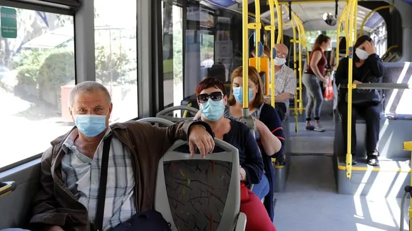Passeggeri con la mascherina a bordo di un autobus - Foto Epa/Antonio Bat