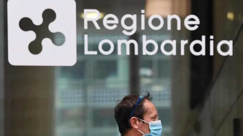 Un passante con mascherina vicino alla sede della Regione Lombardia - Foto Ansa © www.giornaledibrescia.it
