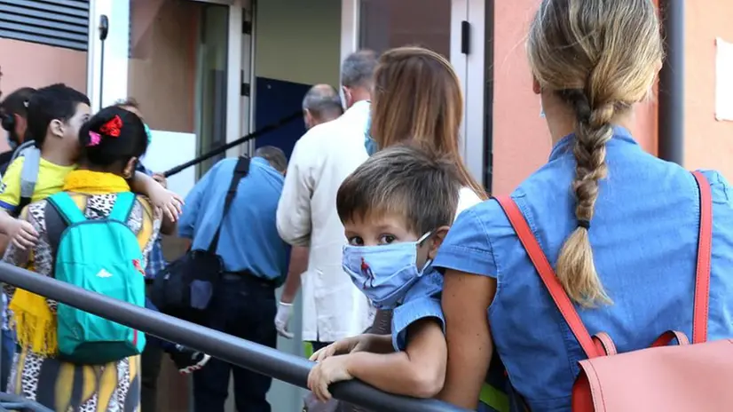 Un bambino della materna in braccio alla mamma - Foto © www.giornaledibrescia.it