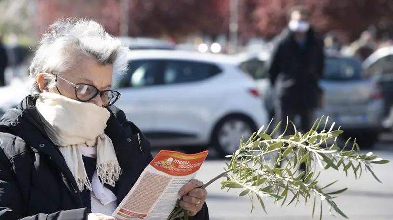 Una signora protegge naso e bocca con una sciarpa - Foto Ansa/Claudio Peri