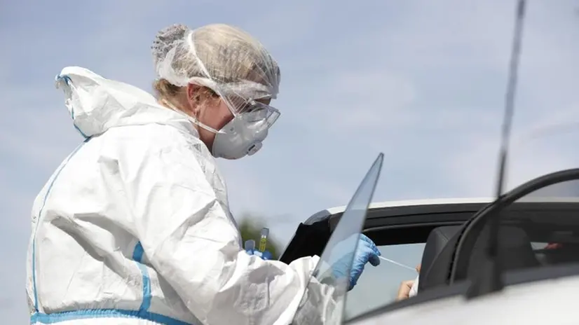 Un'operatrice sanitaria esegue un tampone drive-in - Foto Ansa/Epa/Olivier Hoslet