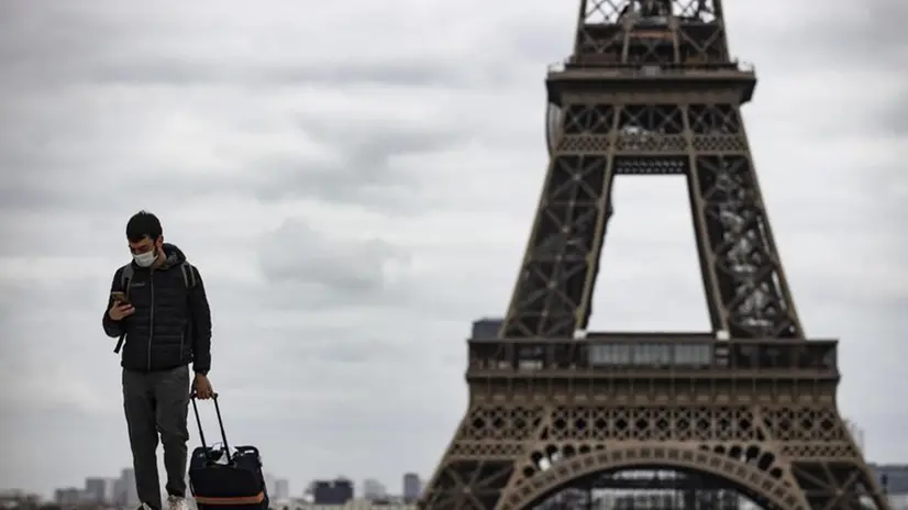 Parigi, un turista con la mascherina: sullo sfondo la torre Eiffel - Foto Epa © www.giornaledibrescia.it