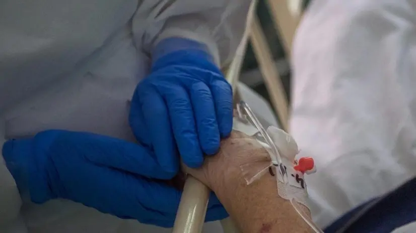 La mano di un'infermiera sostiene quella di una malata - Foto © www.giornaledibrescia.it