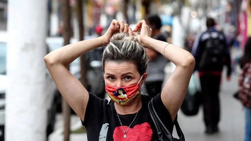 Una donna indossa una mascherina in tessuto per strada - Foto Epa/Sebastiao Moreira