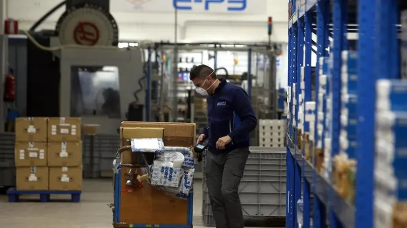 Un operaio al lavoro con la mascherina - Foto Ansa/Matteo Bazzi