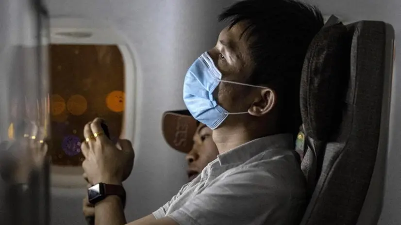 Un passeggero indossa la mascherina durante il volo - Foto Epa/Alex Plavevski