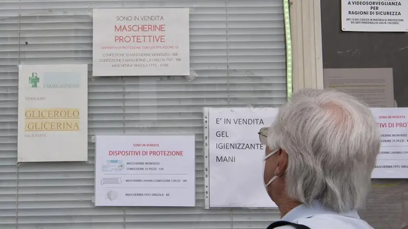 Un uomo legge le indicazioni sui dpi fuori da una farmacia - Foto Ansa/Maurizio Brambatti