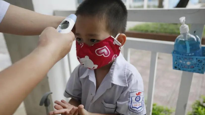 Prova della temperatura per un bambino a Hanoi - Foto Epa/Luong Thai Linh © www.giornaledibrescia.it