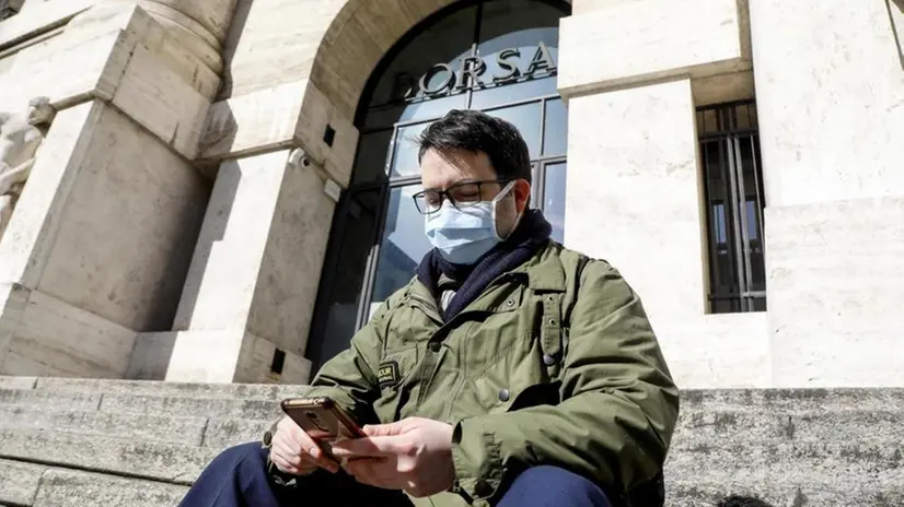 Un ragazzo con la mascherina controlla lo smartphone - Foto Ansa - Mourad Balti Touati © www.giornaledibrescia.it