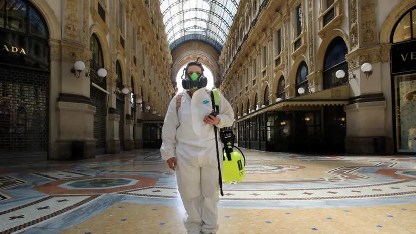 Un'addetta alla disinfezione attraversa la galleria Vittorio Emanuele, a Milano - Foto Ansa © www.giornaledibrescia.it